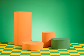 Orange and green podiums in cylinder shaped are decorated on green background. Modern platform for...