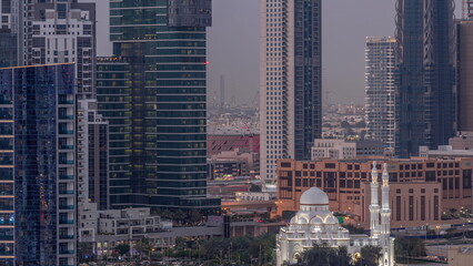 New white mosque near bay avenue surrounded by skyscrapers in Business Bay district aerial day to night timelapse.