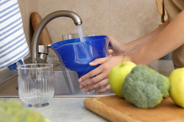 A water filter stands in the kitchen with fresh vegetables