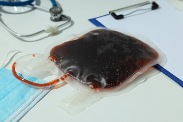A bag of blood on a table with a mask and a stethoscope