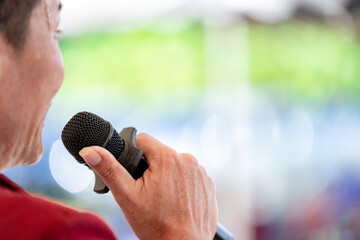 Image of a young man's hand holding a microphone and singing