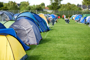 Camping, tents and outdoor music festival in park with people on field with grass or trees in...