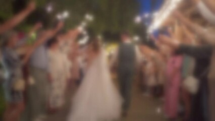 Blurred slow motion, wedding couple is hugging and kissing. Guests with sparklers on night party. Funny event time, festive celebration. Slow motion video. Out of focus video.
