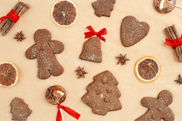 Christmas gingerbread cookies or biscuits on baking paper, winter seasonal traditional bakery with spices, dry orange, cinnamon sticks, anis, candy. Top view sweet food pattern, new year flat lay