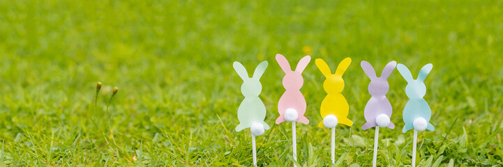 Easter bunnies cut out of colored paper are on green grass background. Easter holiday concept, children's crafts.web banner. copy space.Creative easter composition