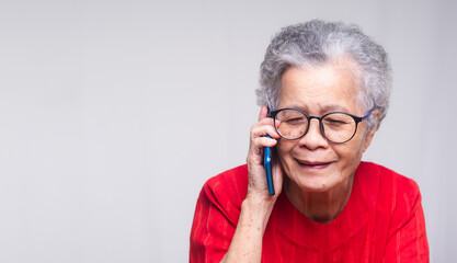 Senior woman with short white hair using a smartphone while sitting at the desk