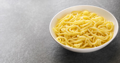 Soup ramen noodles in ceramic bowl on a gray background.
