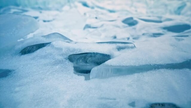 Shimmering piece of ice on snow, winter details. Lake Baikal, Siberia, Russia.