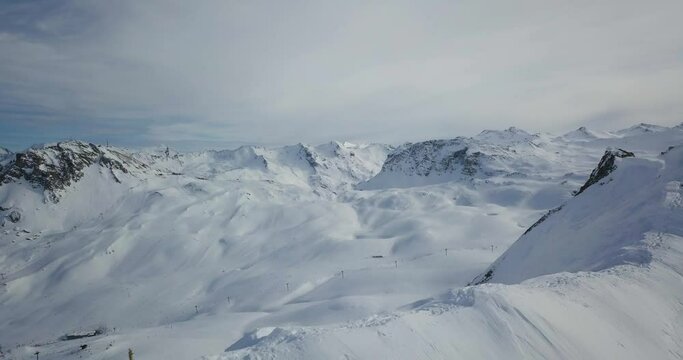 drone footage of france alps ski resort with snow mountains and people skiing 