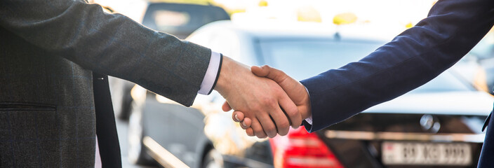 man shaking hands with client in car dealership