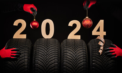 Winter car tires service and hands of mechanics, christmas tree ball and text 2024 happy new year...