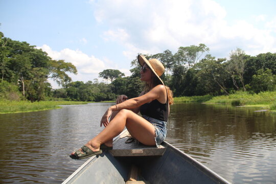 mulher de chap&eacute;u sentada em barco no Rio Croa, em Cruzeiro do Sul, Acre 