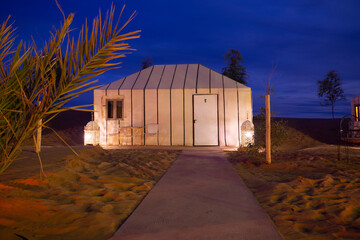 Luxury camp in the Sahara desert, with lights and the typical Haimas. Photo taken at dusk.