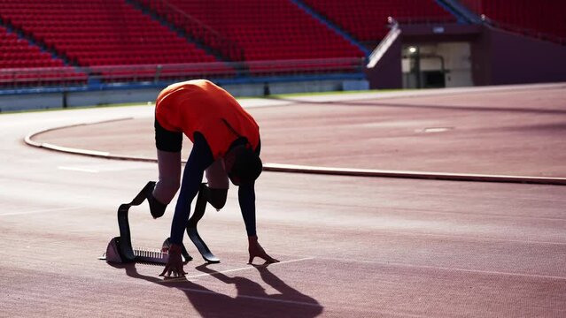 Asian para-athletes with prosthetic blades sprint on a running track at stadium.