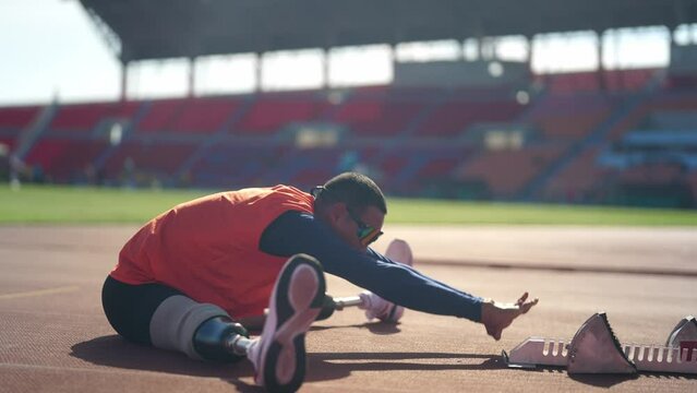Asian para-athletes with prosthetic blades sprint on a running track at stadium.
