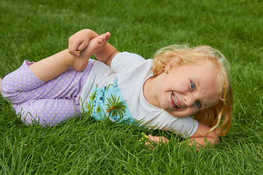angry little girl on the grass,a child lies with bare feet on the grass in the summer