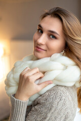 Beautiful young woman wearing merino wool pastel colors scarf enjoying the warm atmosphere. Preparing for the winter season.