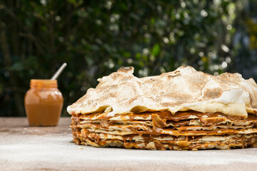 Torta Rogel con pote de dulce de leche sobre una mesa al aire libre