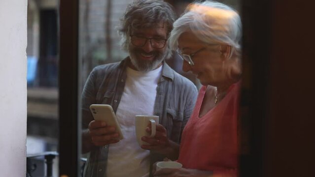 retired couple has a date for Valentine's Day, they look at the photos on their phone remembering moments together while laughing