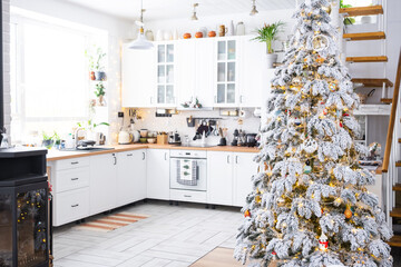 Festive Christmas decor in white kitchen, modern rustic interior with a snowy Christmas tree and...