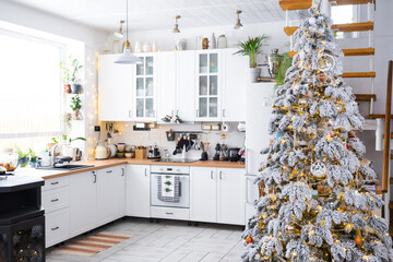 Festive Christmas decor in white kitchen, modern rustic interior with a snowy Christmas tree and...