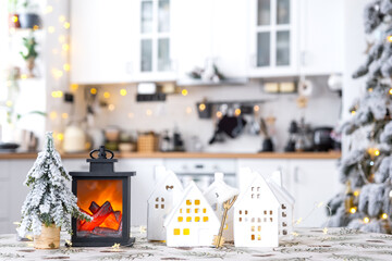 Key and tiny house of a small size on cozy home with Christmas decor on table of festive white kitchen. Gift for New Year. Insurance, moving to new house, mortgage, rent and purchase real estate