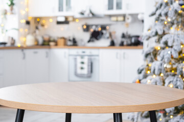 Round empty table to demonstrate the product with space for text in white kitchen, modern interior with a Christmas tree and fairy lights. New Year, Christmas mood, cozy home. 
