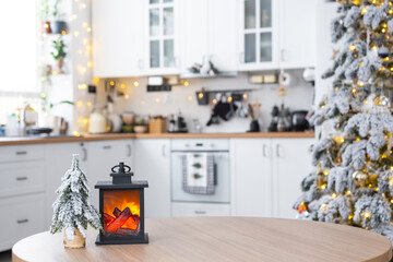 Festive Christmas decor on a round empty table with space for text in white kitchen, modern interior with a Christmas tree and fairy lights. New Year, Christmas mood, cozy home. 