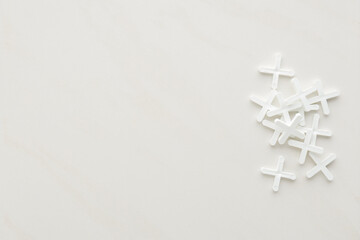 New white plastic crosses for ceramic tile seam. Closeup. Empty place for text on light gray...