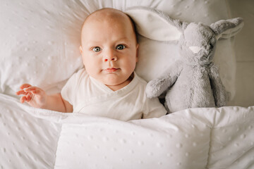 The baby is lying in his crib and looking at the camera . A happy child. Children's article. Copy...