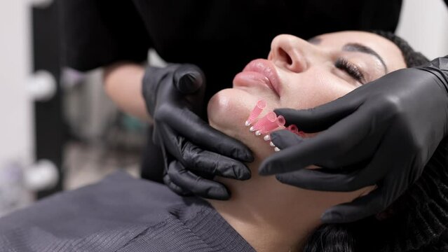 An adult woman undergoes a thread lifting procedure in a cosmetology clinic. Anti-aging facial rejuvenation. A cosmetologist implants cosmetic threads under the skin to eliminate facial ptosis.