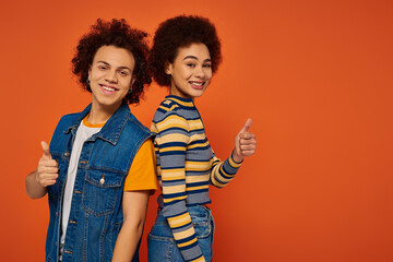 joyous attractive african american siblings posing together and gesturing on orange backdrop