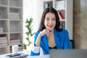 Young Asian business woman sitting working in modern office. Asia business woman sitting smiling and happy with laptop computer in the office.