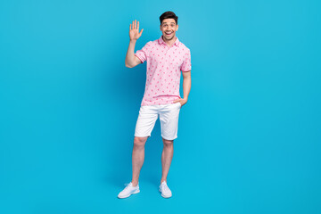 Full length portrait of cheerful young person arm palm waving greeting empty space isolated on blue...