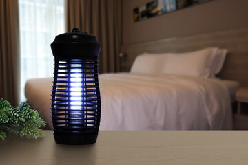 an insects mosquito electric blue light killer lamp is put on the nice wooden table in the nice...