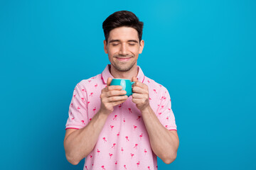 Photo of nice satisfied young man closed eyes smell fresh aroma coffee isolated on blue color...