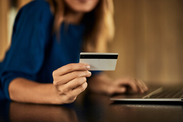 Focus on the woman's hand, holding a credit card, entering the data.