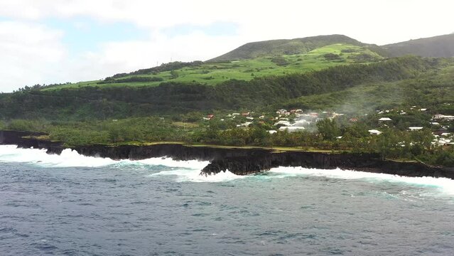 Aerial drone view of Puits des Francais on a stormy day with high breaking waves, cliffs and mountain range in the background, Saint-Philippe, Reunion.