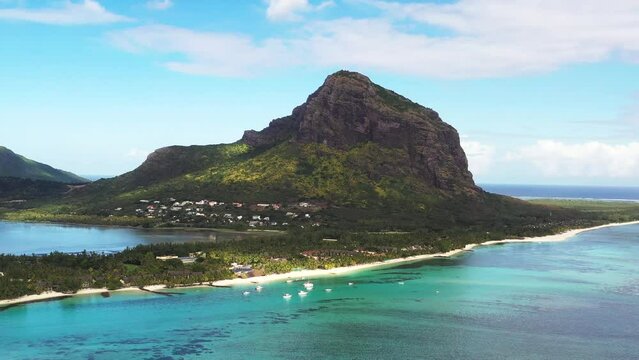 Panoramic aerial drone view of iconic Le Morne mountain with resorts on a peninsula and anchored boats, Le Morne, Black River, Mauritius.