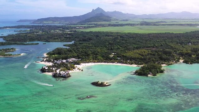 Panoramic aerial view of ShangriLa Le Touessrok and Ilot Mangenie with sailing boats and mountains in the background, Flacq, Mauritius.