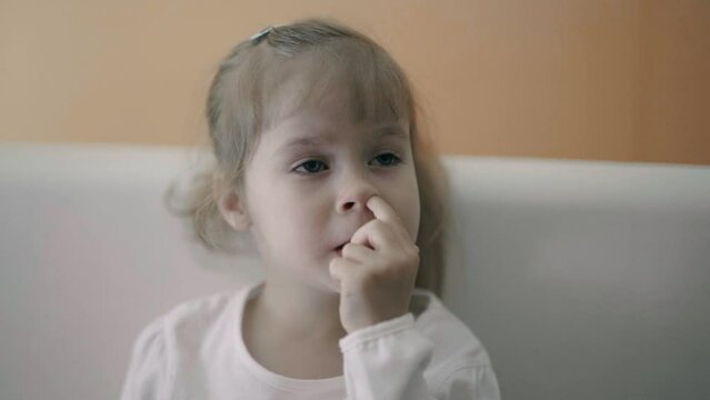 A small child picks his nose.
