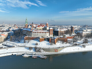 Wawel Castle, Cathedral and Vistula river in winter. Krakow, Poland. Royal Wawel Cathedral and castle with snow in winter. Vistula river and tourist boats. Aerial view with boulevard, promenades - 689673398