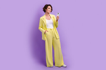 Full length photo of dreamy cute lady wear suit blazer texting modern device isolated violet color background
