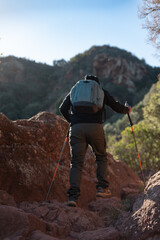 Middle-aged man climbs the mountain in the Garraf Natural Park, supported by hiking poles.