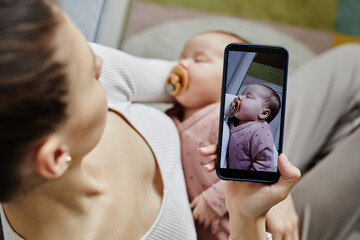 Top view at unrecognizable mother carrying baby and taking photos of her adorable sleeping baby...