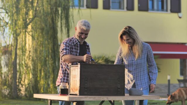 Hobby,happy couple joking laughing in the home garden while restoring painting old furniture