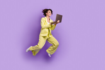 Fototapeta premium Full length photo of carefree sweet lady wear suit blazer jumping high texting modern gadget isolated violet color background