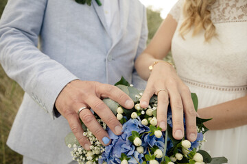 Braut und Bräutigam zeigen ihre Ringe und den Brautstrauß - 689680567