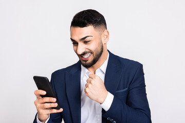 Cheerful attractive turkish man in smart suit holding new modern smartphone observing photos i...