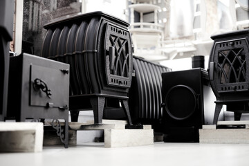 Naklejka premium Black fireplaces with fire at home. New coal-burning stoves on the storefront. Heating in the house concept